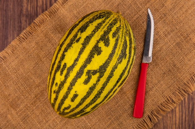 Vista dall'alto di melone cantalupo fresco su un panno di sacco con coltello su una superficie di legno