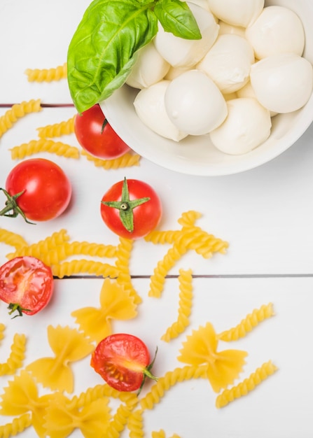 Vista dall&#39;alto di mozzarella italiana con foglia di basilico; pomodori e fusilli