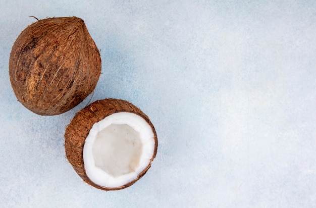 Vista dall'alto di noci di cocco marroni e fresche su bianco con spazio di copia