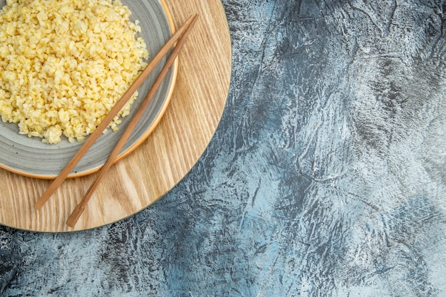 Vista dall'alto di orzo perlato cotto con bastoncini sulla superficie chiara