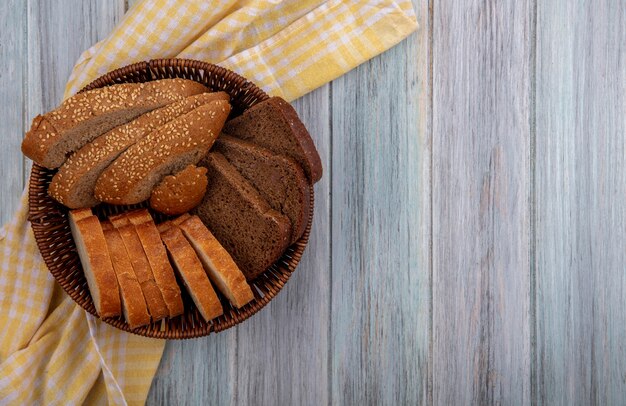 Vista dall'alto di pane come fette di pannocchia marrone segale e quelli croccanti nel cestello su panno plaid su sfondo di legno con spazio di copia