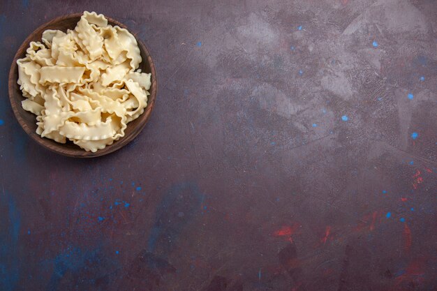 Vista dall'alto di pasta cruda a fette all'interno del piatto marrone sulla cena di pasta alimentare pasta pasto scrivania scura
