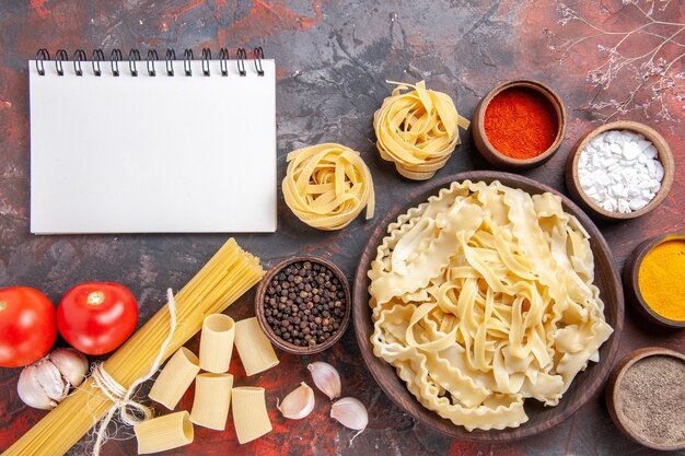 Vista dall'alto di pasta cruda a fette con condimenti su cibo scuro pasta pasta superficie scura