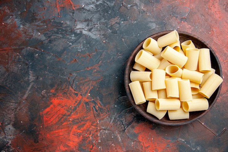 Foto gratuito vista dall'alto di pasta cruda all'interno della pentola sul lato sinistro del tavolo nero