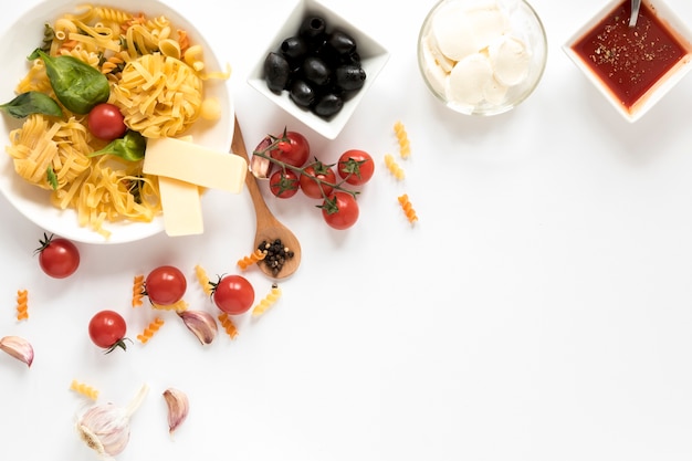 Vista dall&#39;alto di pasta cruda ed è ingredienti isolati su superficie bianca