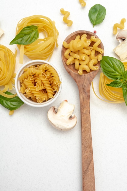 Vista dall'alto di pasta e cucchiaio di legno su sfondo chiaro