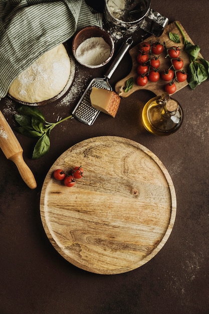 Vista dall'alto di pasta per pizza con tavola di legno e pomodori