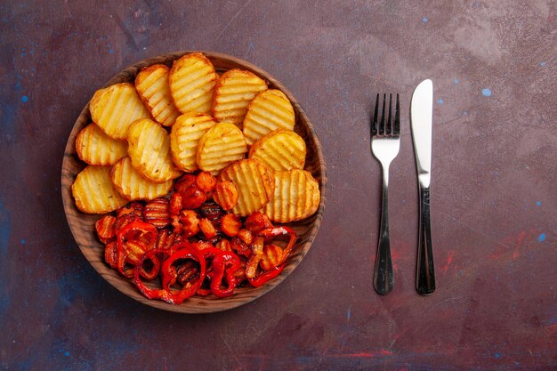 Vista dall'alto di patate al forno con verdure cotte all'interno del piatto nello spazio buio