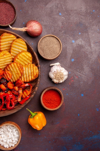 Vista dall'alto di patate al forno con verdure cotte su uno spazio buio