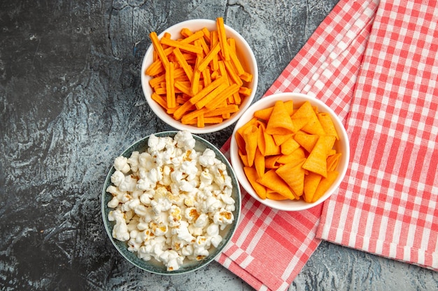 Vista dall'alto di patatine al formaggio con popcorn e fette biscottate sulla superficie chiara