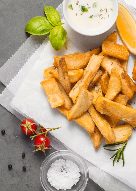 Vista dall'alto di patatine fritte con ciotola di salsa e sale