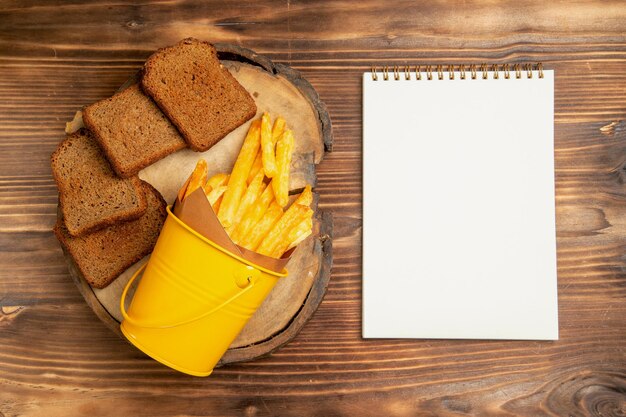 Vista dall'alto di patatine fritte con pane scuro sul tavolo marrone