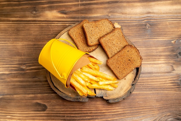 Vista dall'alto di patatine fritte con pane scuro sul tavolo marrone