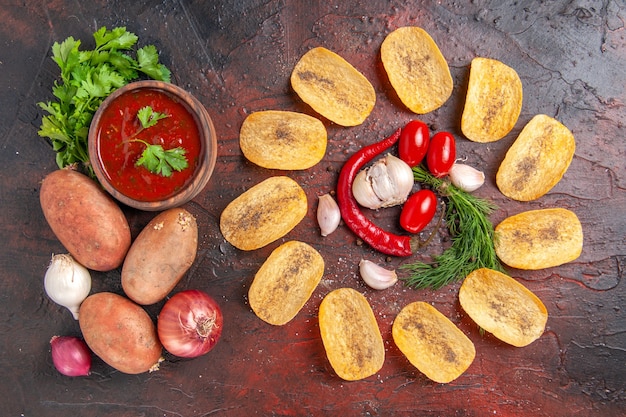 Vista dall'alto di patatine fritte deliziose fatte in casa peperoncino rosso aglio pomodori verdi ketchup patate cipolla sul tavolo scuro