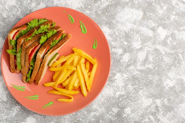Vista dall'alto di patatine fritte e panini all'interno del piatto di pesche sulla superficie chiara grigia