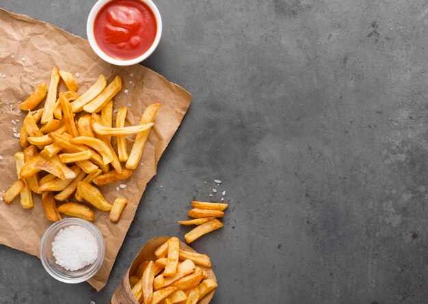 Vista dall'alto di patatine fritte su carta con sale e copia spazio