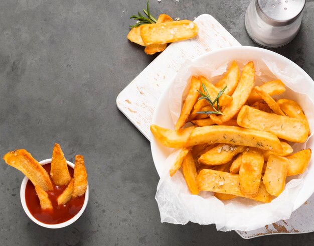 Vista dall'alto di patatine fritte sulla piastra con ketchup e saliera