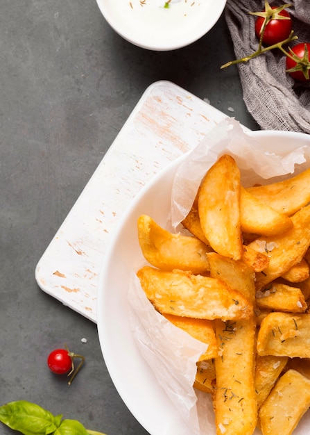 Vista dall'alto di patatine fritte sulla piastra con pomodori e salsa speciale