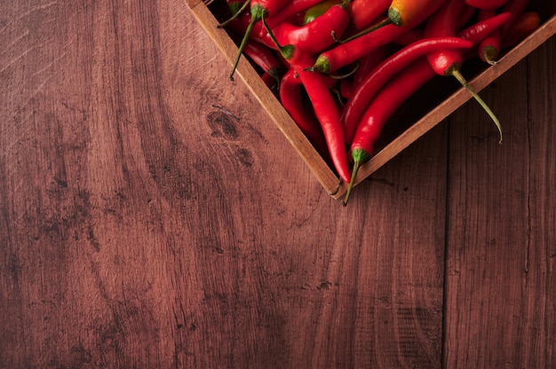 Vista dall'alto di peperoncino rosso in una scatola su una superficie di legno con spazio per il testo
