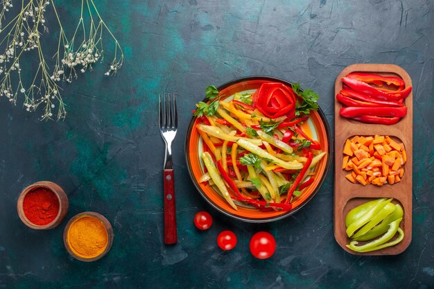 Vista dall'alto di peperoni affettati gustosa insalata sana con condimenti e altre verdure su sfondo scuro