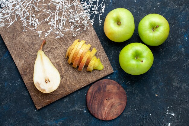 Vista dall'alto di pere fresche intere affettate e dolci con mele verdi sulla scrivania blu scuro, frutta dolce salute alimentare