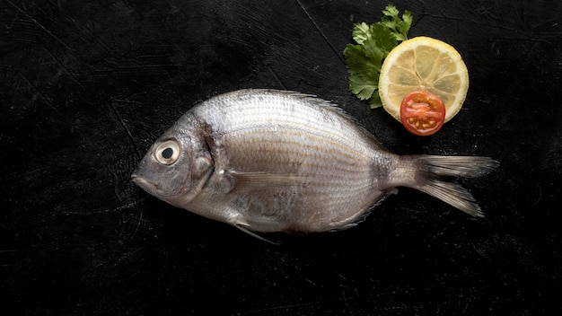 Vista dall'alto di pesce con fetta di limone e pomodoro