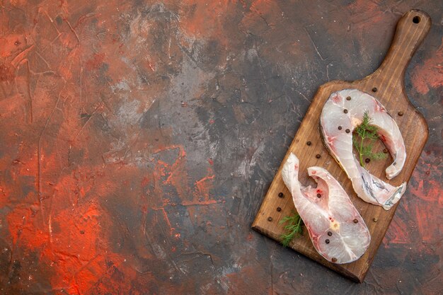 Vista dall'alto di pesce crudo fresco e pepe sul tagliere di legno sulla superficie di colore della miscela