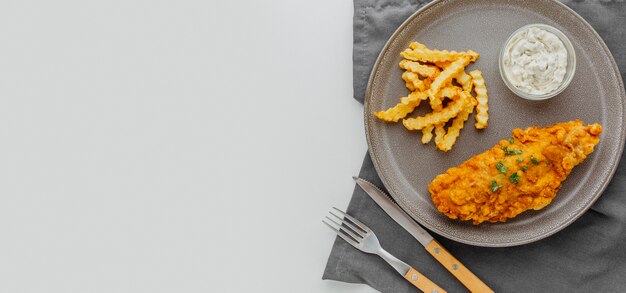 Vista dall'alto di pesce e patatine fritte sulla piastra con copia spazio