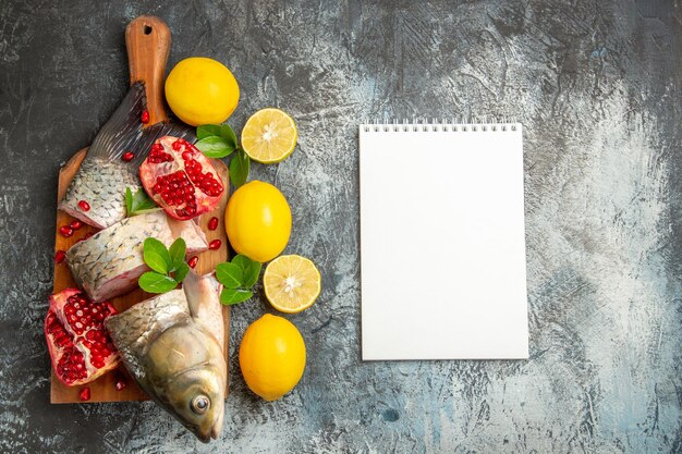 Vista dall'alto di pesce fresco a fette con melograni e limone sulla superficie chiara