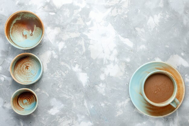 Vista dall'alto di piatti vuoti con caffè al latte sulla scrivania leggera, bere caffè al latte delizioso