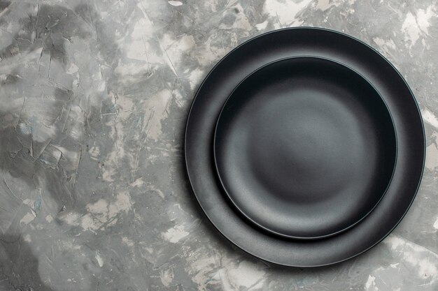 Vista dall'alto di piatti vuoti rotondi di colore nero su superficie grigia