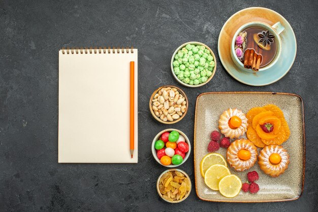 Vista dall'alto di piccole deliziose torte con caramelle, frutta e noci sul tavolo grigio