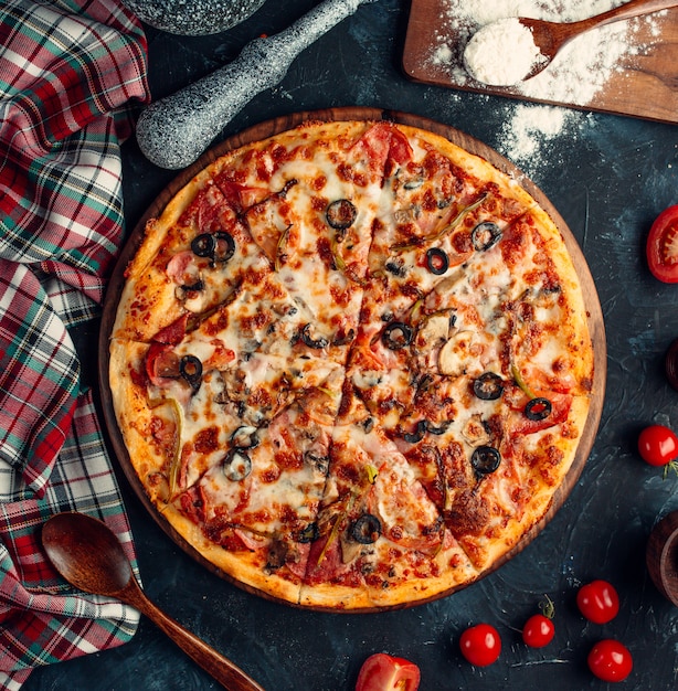 vista dall'alto di pizza mista con pomodoro, olive nere e formaggio fuso