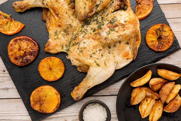 Vista dall'alto di pollo al forno con fette d'arancia e spicchi