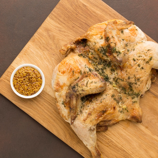 Vista dall'alto di pollo al forno sul tagliere con senape di Digione