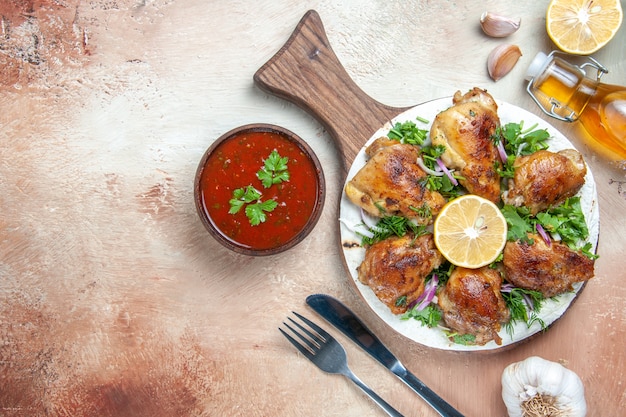 Vista dall'alto di pollo pollo con limone erbe cipolla sul coltello forchetta salsa olio bordo