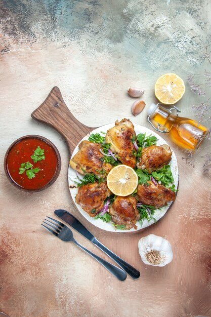 Vista dall'alto di pollo pollo con limone erbe cipolla sulla tavola aglio olio salsa forchetta coltello