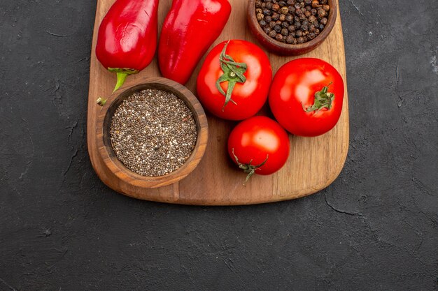 Vista dall'alto di pomodori freschi con condimenti e peperoncino su nero