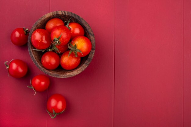 Vista dall'alto di pomodori in ciotola e sulla superficie rossa