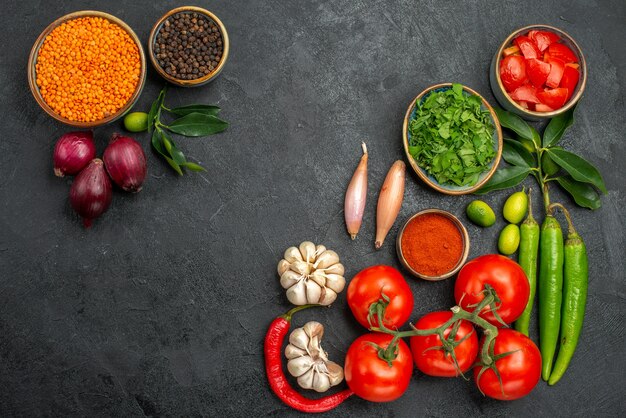 Vista dall'alto di pomodori pomodori peperoncino spezie erbe ciotola di lenticchie cipolla pepe nero