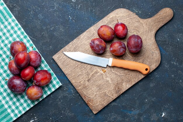 Vista dall'alto di prugne fresche intere morbide e succose sulla scrivania scura, bacche di frutta fresca