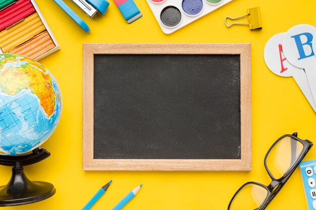 Vista dall'alto di ritorno a materiale scolastico con lavagna e occhiali