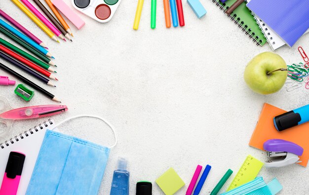 Vista dall'alto di ritorno a materiale scolastico con matite e mela