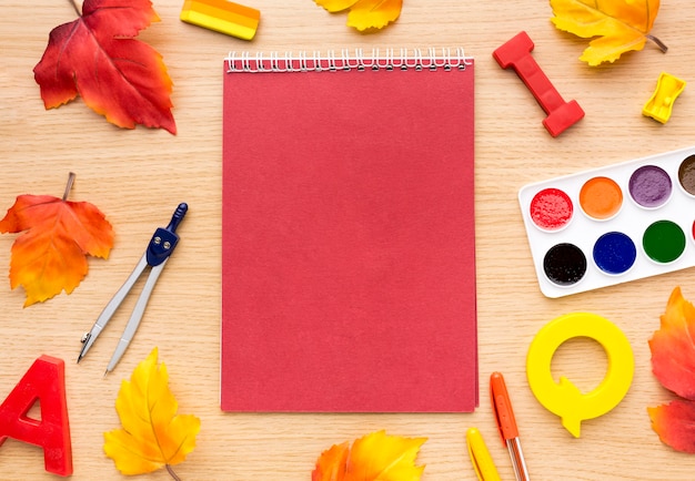 Vista dall'alto di ritorno a materiale scolastico con quaderno e foglie