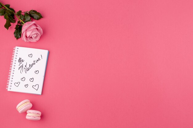 Vista dall'alto di rosa e notebook con macarons e copia spazio