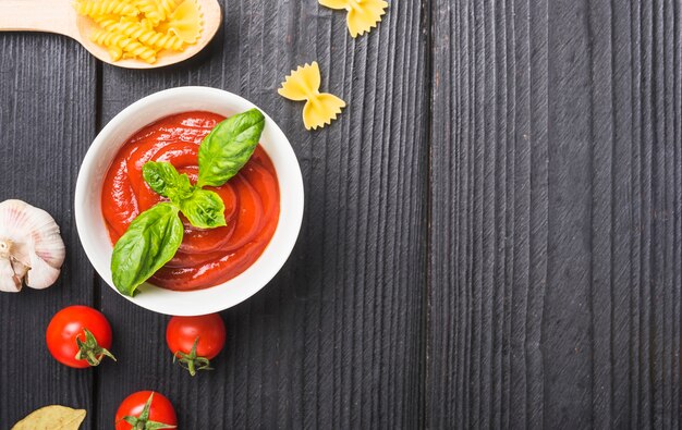 Vista dall&#39;alto di salsa di pomodoro con aglio e pasta sulla tavola di legno