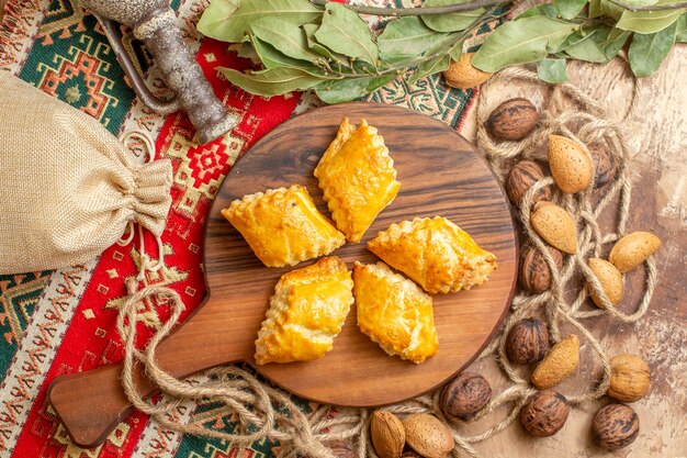 Vista dall'alto di squisiti pasticcini a base di noci con noci fresche sulla scrivania marrone