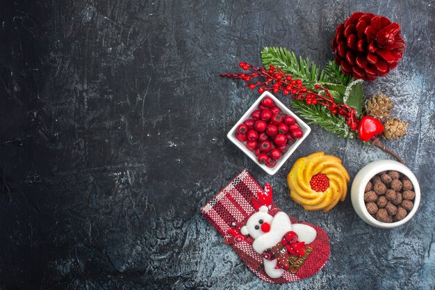 Vista dall'alto di un delizioso biscotto accessorio per la decorazione del calzino di Babbo Natale e del cornell in una ciotola con rami di abete su superficie scura dark