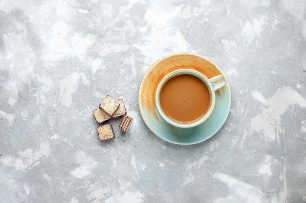 Vista dall'alto di un delizioso caffè al latte con cialde sulla scrivania bianca, dolce caffè espresso al latte