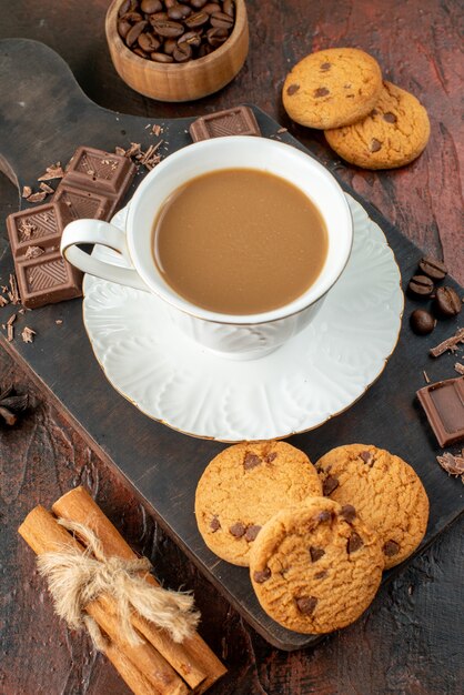 Vista dall'alto di un delizioso caffè in tazza bianca su tagliere di legno biscotti cannella lime barrette di cioccolato